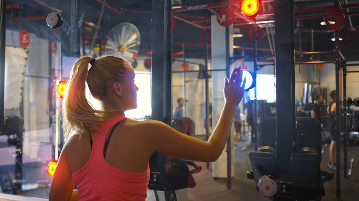 Young female training with wall-mounted BlazePod flash reflex reaction lights