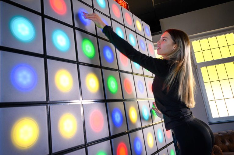 Young female positive gaming with twall® A Series interactive reaction wall with LED lights