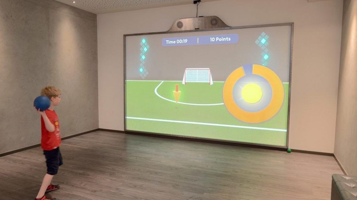 MultiBall 7 Young boy throws ball at screen while playing MultiBall exergaming multi-sports gaming wall for interactive sports and leisure