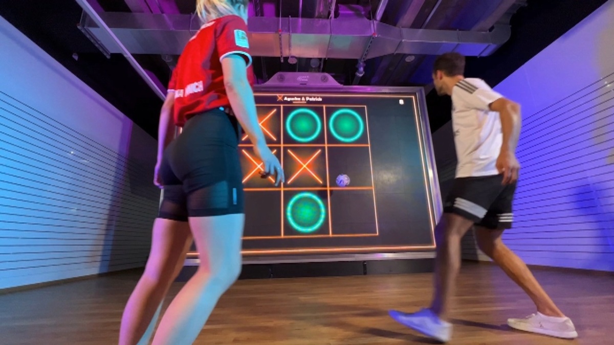 MultiBall 10 Young female and male compete with soccer ball on MultiBall exergaming multi-sports gaming wall