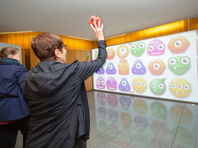 MultiBall 11 Older lady plays MultiBall exergaming multi-sports gaming wall for interactive sports and leisure