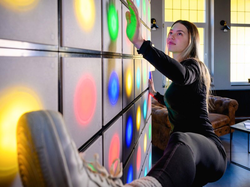 twall® 2 Young woman uses hands and feet to hit targets on twall® A Series light reaction wall with 64 LEDs