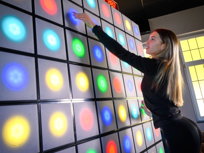 twall® 3 Young female touches lights on twall® A Series interactive reaction wall with 64 LEDs
