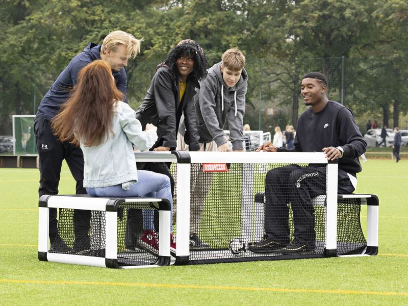 Subsoccer® 6 Female and male compete outdoors in park while other watch Subsoccer® table football game