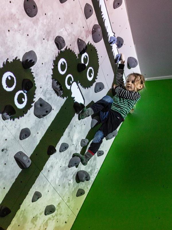 ValoClimb 1 Young girl climber at top of wall on Valo Motion ValoClimb immersive climbing wall with Shadowlings game for interactive sports and leisure